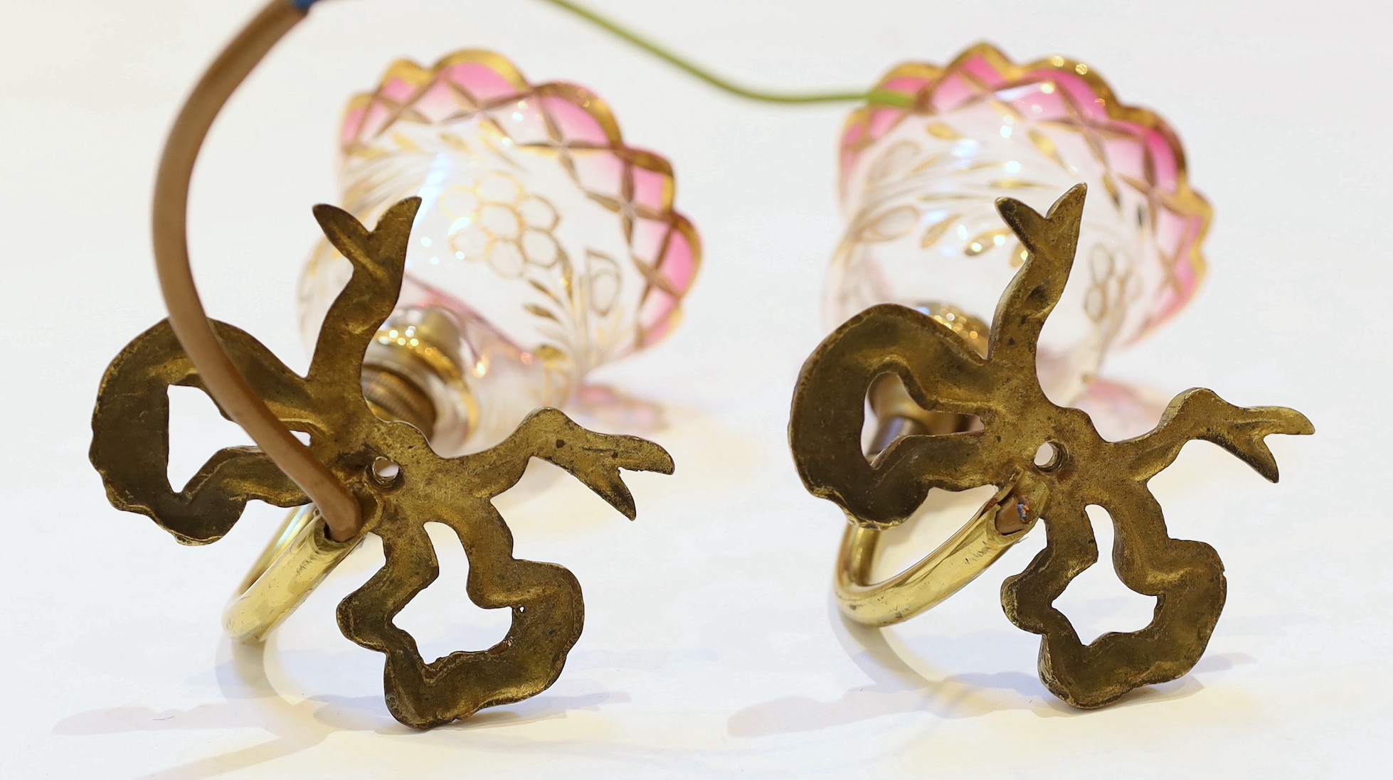 A pair of 1920s brass wall lights with frosted flame glass shades and a pair of brass ribbon back wall lights with lustre shades, height 14cm & height 12cm